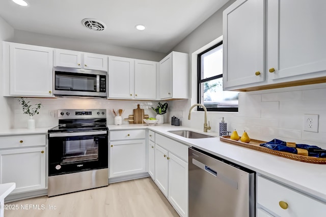 kitchen with visible vents, appliances with stainless steel finishes, white cabinets, and a sink