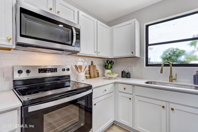 kitchen with stainless steel appliances, backsplash, a sink, and white cabinets