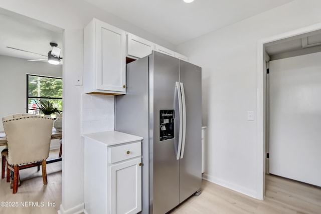 kitchen featuring light countertops, stainless steel fridge, light wood-style flooring, and white cabinets