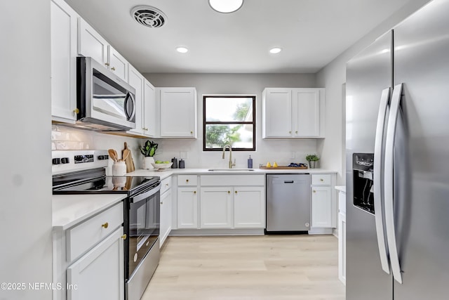 kitchen featuring appliances with stainless steel finishes, a sink, visible vents, and white cabinets