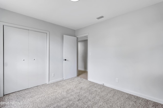 unfurnished bedroom with carpet floors, visible vents, and a closet