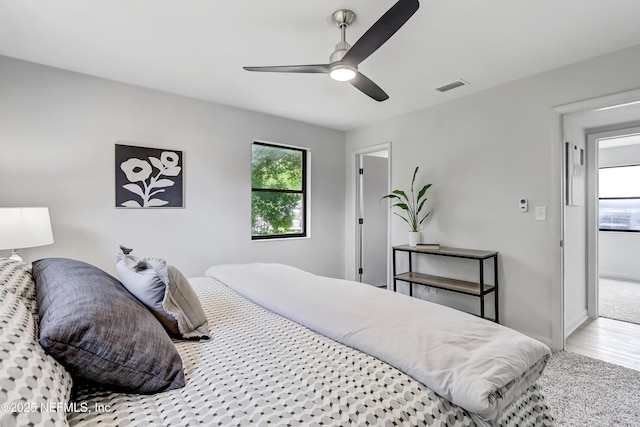 bedroom featuring a ceiling fan, visible vents, baseboards, and wood finished floors