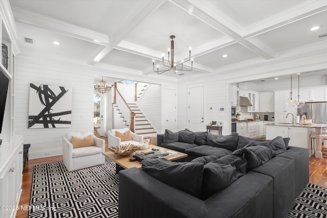 living area with a chandelier, dark wood finished floors, beamed ceiling, and stairway