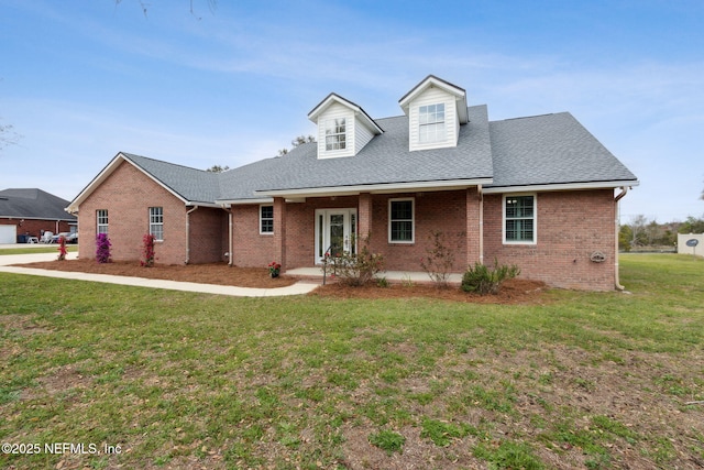 view of front facade with a front yard, brick siding, and roof with shingles