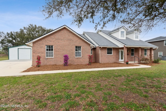 view of front of house with driveway, a detached garage, an outbuilding, a front lawn, and brick siding