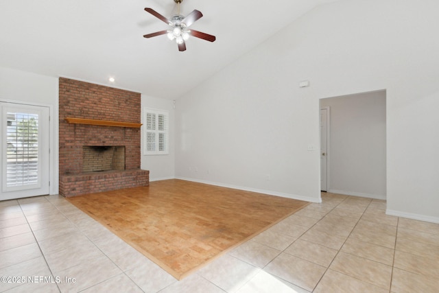 living room with light tile patterned floors, baseboards, a ceiling fan, a brick fireplace, and high vaulted ceiling