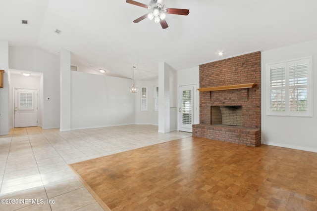 unfurnished living room with light tile patterned floors, visible vents, ceiling fan, vaulted ceiling, and a brick fireplace