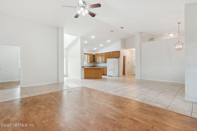 unfurnished living room with visible vents, baseboards, light tile patterned flooring, high vaulted ceiling, and ceiling fan with notable chandelier