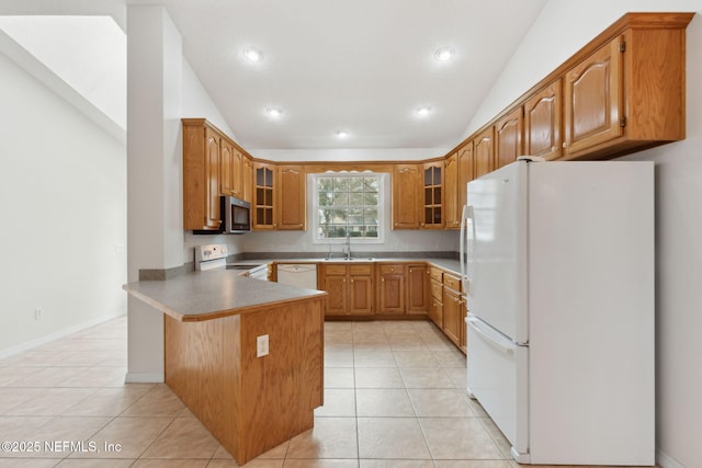 kitchen with light tile patterned floors, a peninsula, white appliances, vaulted ceiling, and glass insert cabinets