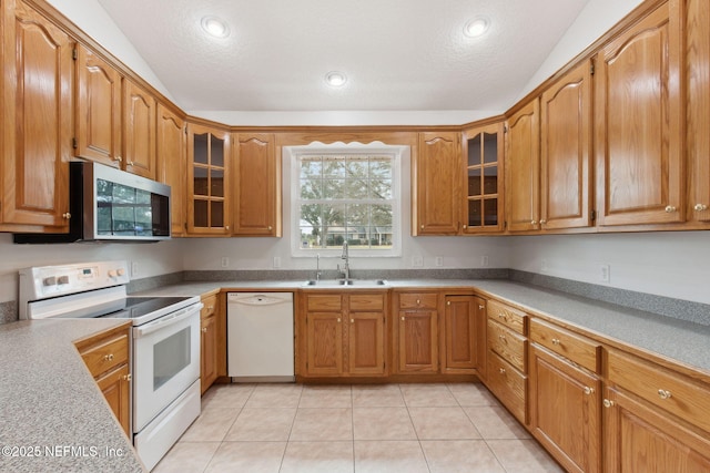 kitchen with glass insert cabinets, lofted ceiling, white appliances, and a sink