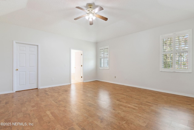 spare room featuring ceiling fan, light wood-style flooring, and baseboards