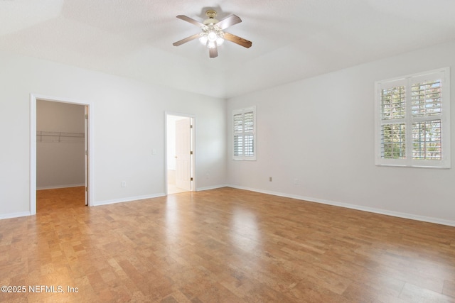 empty room featuring light wood-style floors, baseboards, and a ceiling fan