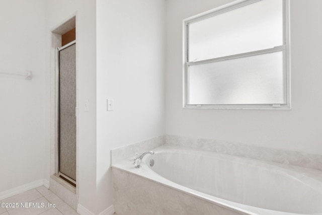 bathroom featuring tile patterned flooring, baseboards, a bath, and a shower stall