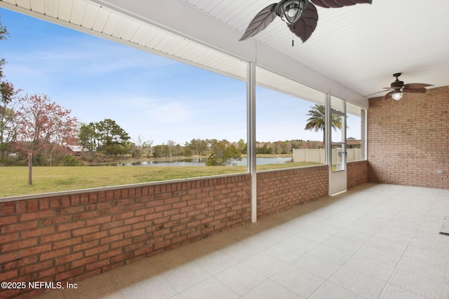 unfurnished sunroom featuring a water view and a ceiling fan