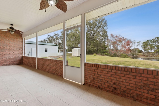 unfurnished sunroom featuring a water view and a ceiling fan