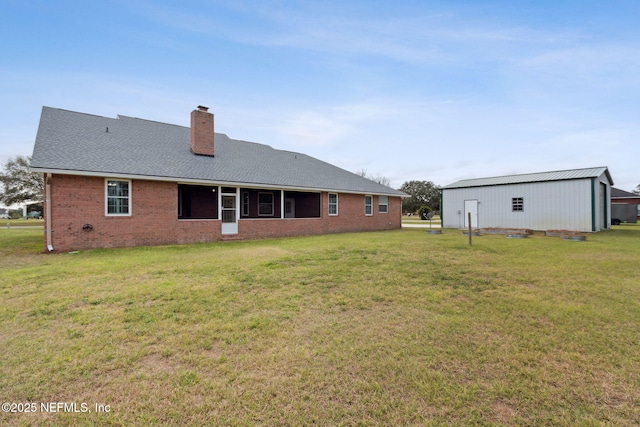 back of house with an outbuilding, brick siding, a lawn, and a chimney