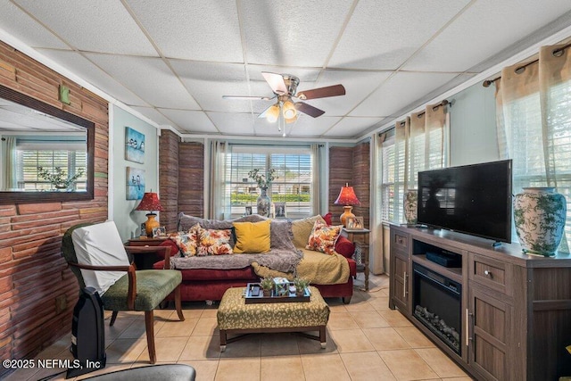 living area with light tile patterned floors, a drop ceiling, and a ceiling fan