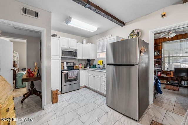 kitchen featuring visible vents, appliances with stainless steel finishes, white cabinetry, beamed ceiling, and marble finish floor