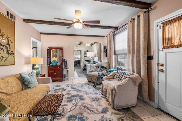 living area featuring light tile patterned floors, beamed ceiling, arched walkways, and visible vents