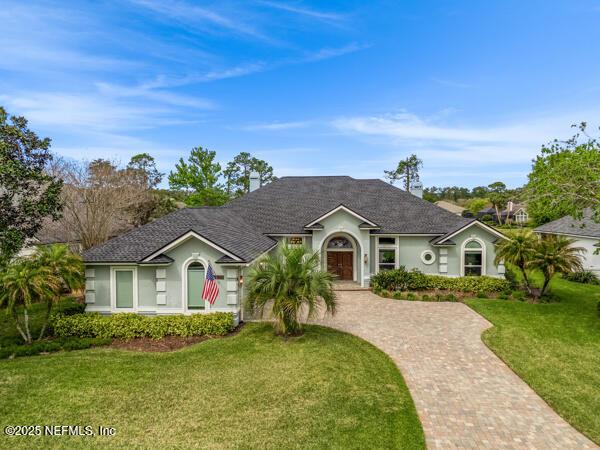 ranch-style home with decorative driveway, a front yard, and stucco siding