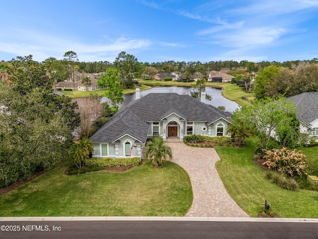 view of front of home featuring decorative driveway, a water view, and a front lawn