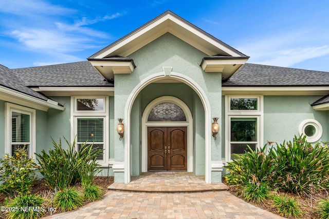 doorway to property with a shingled roof and stucco siding