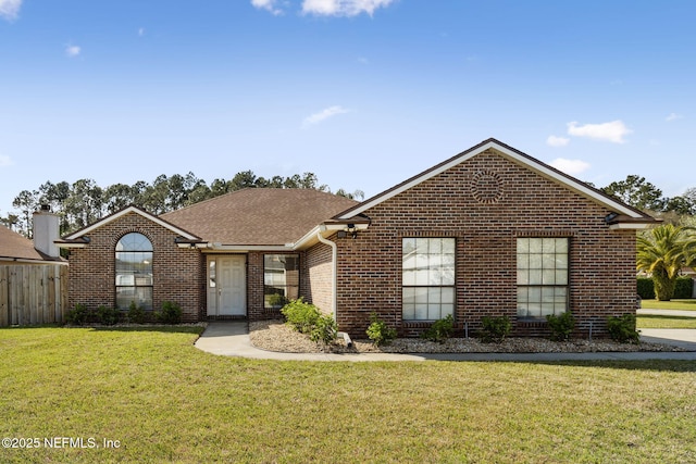 single story home featuring brick siding, roof with shingles, and a front yard