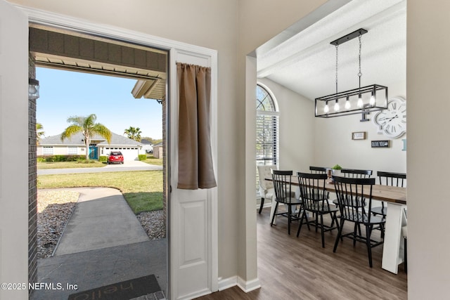 entrance foyer featuring an inviting chandelier, wood finished floors, baseboards, and vaulted ceiling