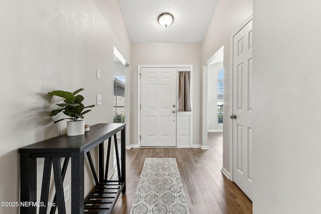 entryway with baseboards, a textured ceiling, and wood finished floors