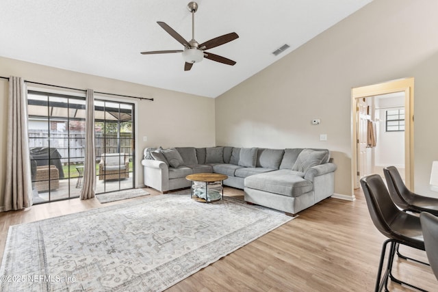 living room featuring visible vents, baseboards, light wood-type flooring, lofted ceiling, and a ceiling fan