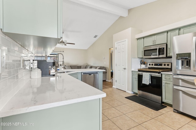 kitchen with green cabinetry, light tile patterned flooring, a sink, decorative backsplash, and appliances with stainless steel finishes