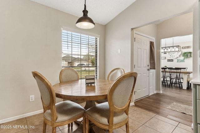 dining area with vaulted ceiling, light tile patterned floors, baseboards, and a chandelier