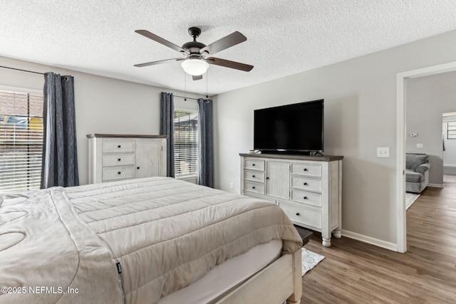 bedroom featuring a textured ceiling, a ceiling fan, baseboards, and wood finished floors