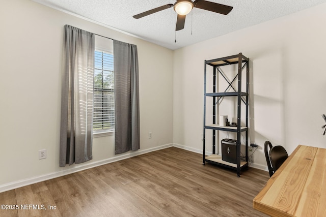 unfurnished office featuring baseboards, a textured ceiling, a ceiling fan, and wood finished floors