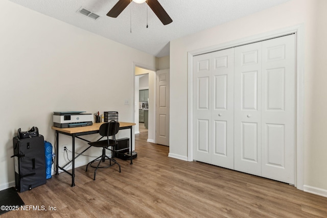 office area with visible vents, baseboards, wood finished floors, and a ceiling fan