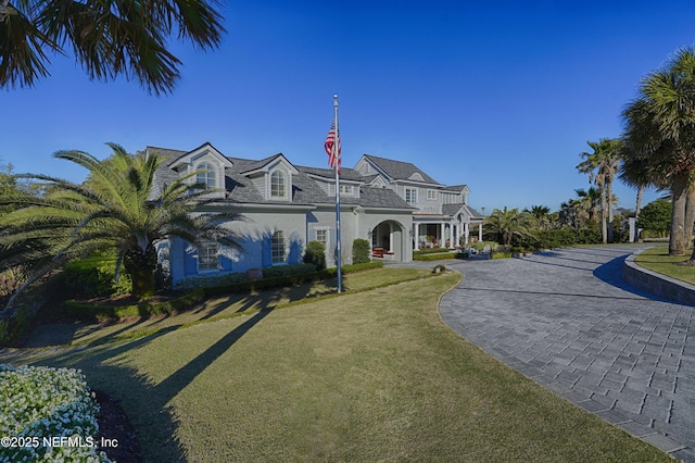 view of front of house with curved driveway and a front lawn