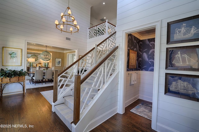 stairs featuring a notable chandelier, crown molding, a high ceiling, and wood finished floors