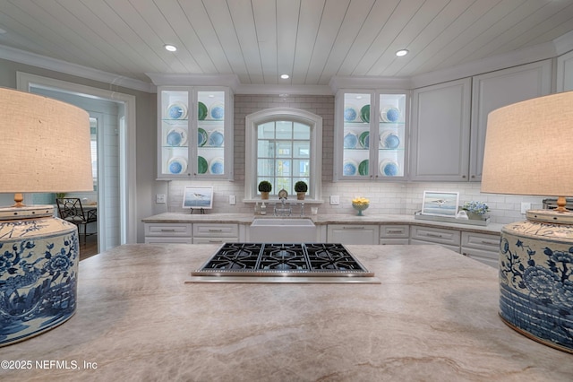 kitchen featuring a sink, cooktop, backsplash, and white cabinetry