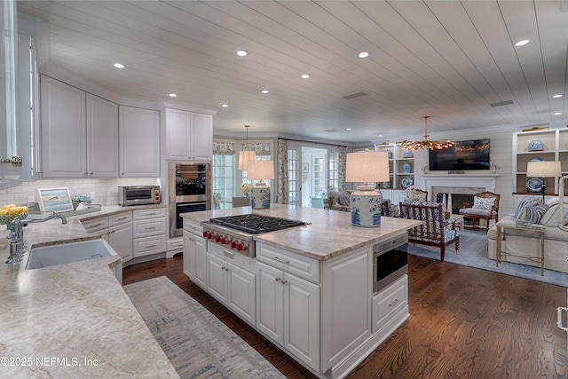 kitchen featuring a sink, open floor plan, stainless steel appliances, a fireplace, and dark wood-style flooring