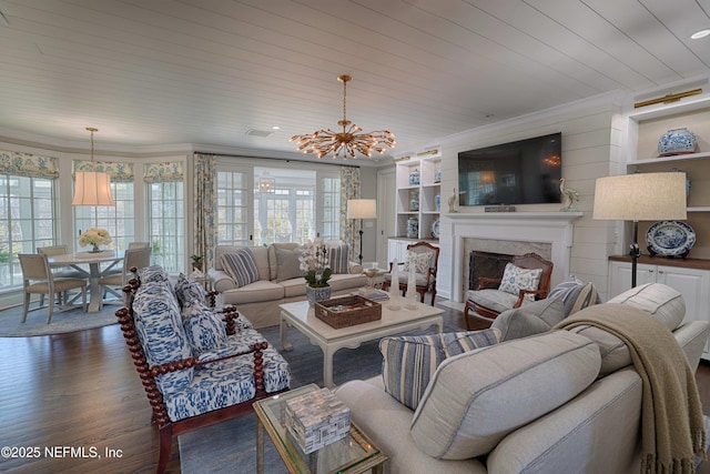 living area with built in features, a high end fireplace, crown molding, a chandelier, and dark wood-style flooring