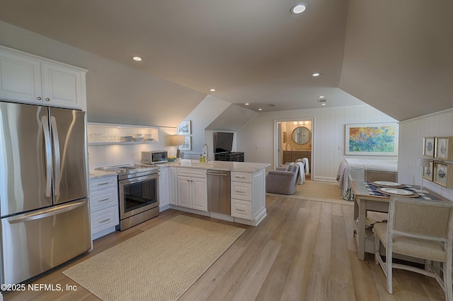 kitchen featuring appliances with stainless steel finishes, white cabinetry, lofted ceiling, and a peninsula