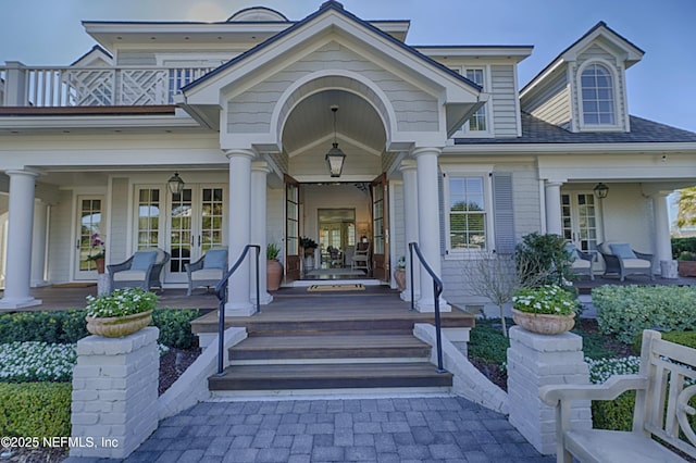 entrance to property with covered porch, french doors, and a balcony