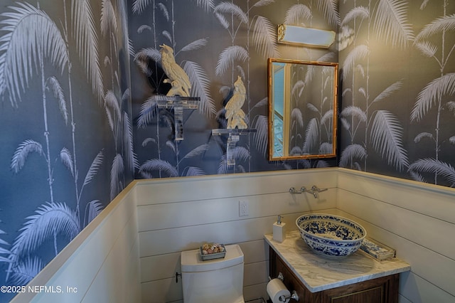 interior space with toilet, wallpapered walls, and vanity