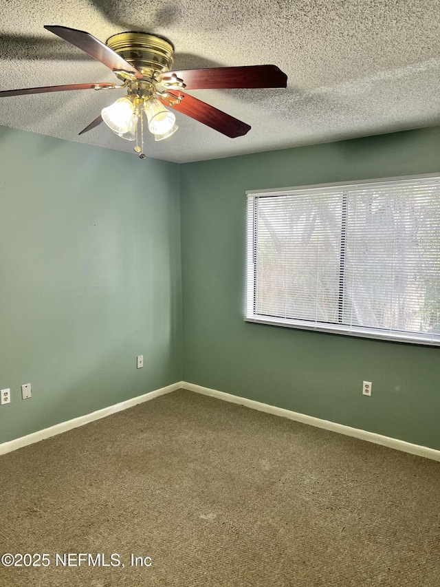 carpeted spare room with a ceiling fan, baseboards, and a textured ceiling