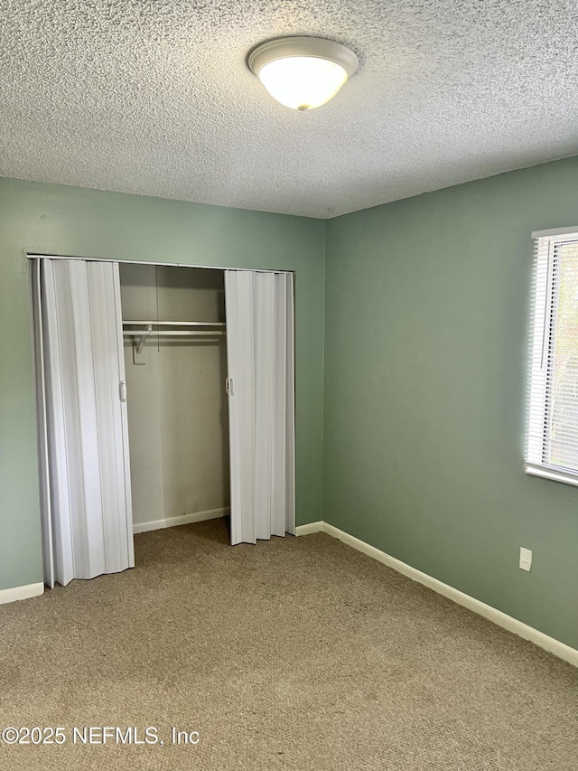 unfurnished bedroom featuring a textured ceiling, a closet, carpet, and baseboards