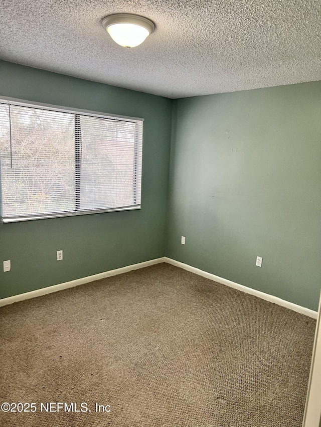 carpeted empty room featuring a textured ceiling and baseboards