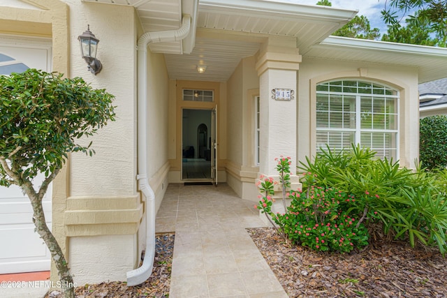 view of exterior entry featuring a garage and stucco siding