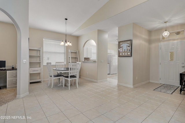 dining room featuring an inviting chandelier, arched walkways, vaulted ceiling, and light tile patterned flooring