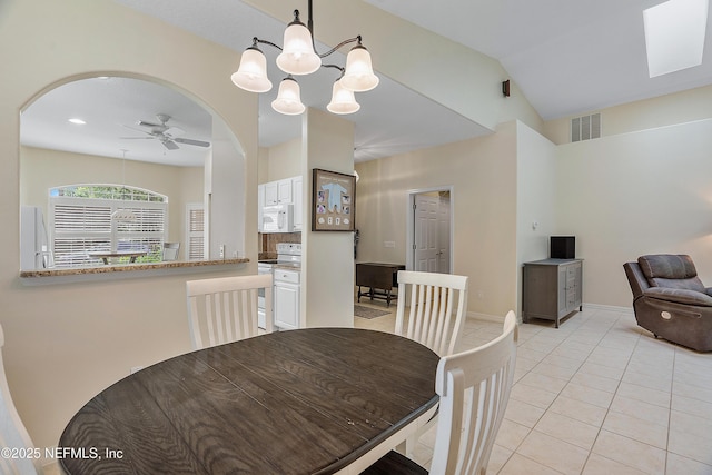 dining space featuring light tile patterned floors, ceiling fan, arched walkways, visible vents, and vaulted ceiling