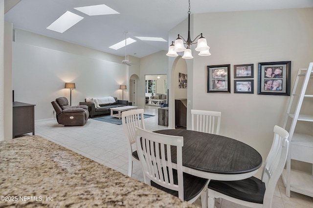 dining space featuring a chandelier, lofted ceiling, light tile patterned flooring, and arched walkways